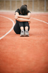 Wall Mural - Today has been tough. Shot of a young woman looking upset while sitting on the track.