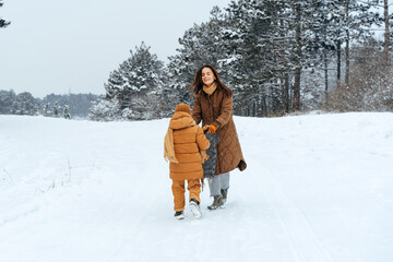 Wall Mural - Woman with a little son on a winter hike in the snowy forest