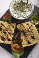 Vertical shot of two pieces of bulgur dish with a sauce and salad on a tray.