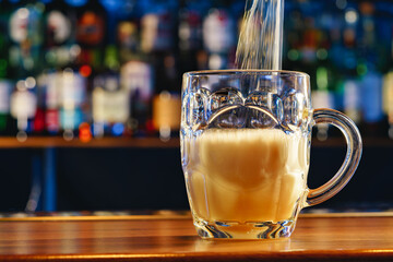 Wall Mural - Pouring draft beer into a glass on bar background