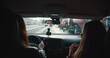 © vadim_key - Rear view inside car, female taxi driver in face mask talks to passenger while driving and turning along city streets.