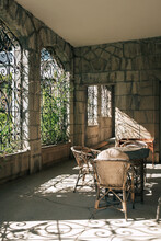 Sunlight Go Through Wrought Iron Lattice In Summer Veranda In Medieval Style With Wicker Furniture.