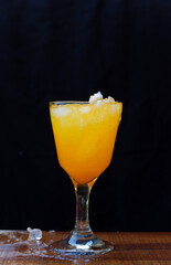 Poster - Closeup of an orange cocktail with ice on black background