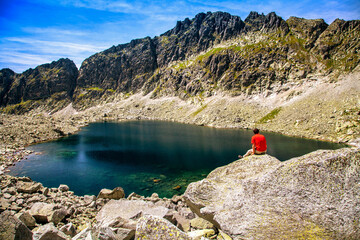 Wall Mural - Hiker sitting on the rock and looking on lake and mountains in High Tatras at Slovakia