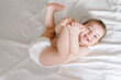 © Татевик Багдасарян - happy joyful baby in diapers lying on white bed