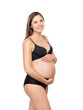 Young pregnant woman in black swimsuit. Girl expecting a baby and touching her belly isolated on white background.
