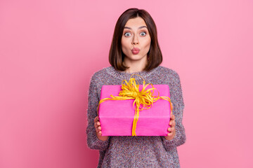 Poster - Portrait of attractive amazed girl holding in hands festal gift sending air kiss isolated over pink pastel color background