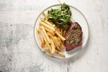 Top down view of steak with salsa verde, chips and green salad