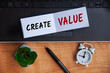 © JeromeMaurice - Create value text on notepad with laptop, clock, pen and wooden background. Business concept