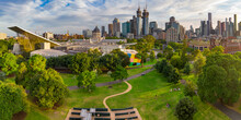 Aerial View Of A Green Inner City Park With A City Skyline Behind