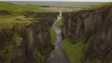 Aerial Dolly In Of Fjaðrá River Flowing Through Fjaðrárgljúfur Verdant Canyon Steep Rock Walls At Daytime,Iceland