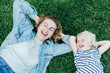 © Ilona - Top view of carefree laughing mother and daughter lying on green grass and enjoying summer