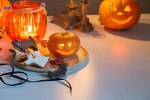 Halloween Pumpkins With Burning Candles On White Table