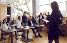 Business. Female CEO Answers Audience's Questions During Working Meeting In Modern Loft-style Office. Unknown Female Leader, Trainer, Speaks At Briefing Or Seminar In Question And Answer Format.