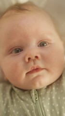 vertical format portrait video of cute newborn baby lying on the back in child crib. playful portrai