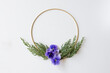 Gold frame with greenery and pansies on a white background