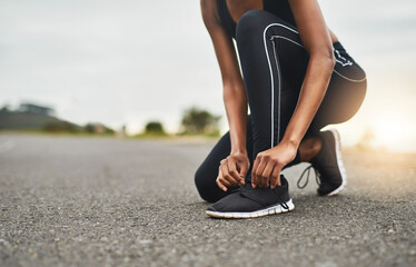 Canvas Print - Run as fast as you can. Closeup shot of a sporty woman tying her shoelaces while exercising outdoors.