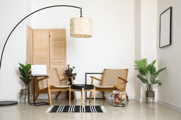 Interior of stylish room with comfortable armchairs and modern floor lamp near light wall