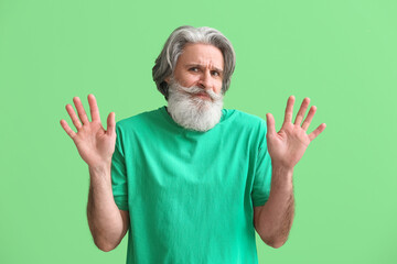 Poster - Upset senior man in t-shirt on green background