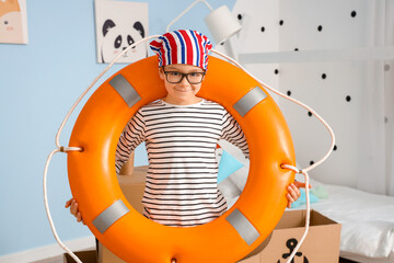 Wall Mural - Funny little boy playing with cardboard ship and lifebuoy at home