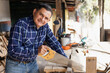 © Fernanda - Hispanic man working with saw in his carpentry workshop-Latin Carpenter working