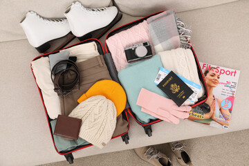 Canvas Print - Open suitcase with warm clothes, accessories and shoes on sofa indoors, top view