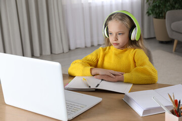 Wall Mural - Cute little girl with modern laptop studying online at home. E-learning