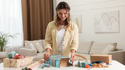 Poster - Beautiful young woman wrapping gift at table in living room