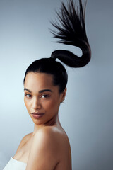 Wall Mural - Never underestimate the power of a good haircut. Studio shot of an attractive young woman holding her hair against a grey background.