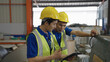 © suwanb - Two Asian workers industry walking and inspecting the machine with tablets in the factory.