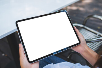 Mockup image of a woman holding digital tablet with blank white desktop screen in the outdoors