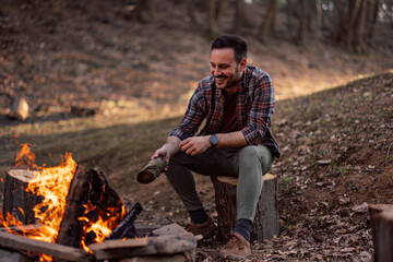 photo of a man enjoying around the campfire, sitting alone.