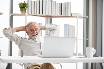 Wall Mural - senior businessman looking laptop computer and stretching on a table when taking a break