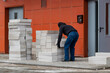 © Anoo - A man carries foam concrete blocks to the construction site, Preparing for construction work. The erection of walls in a residential building.