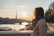 © Julija - Young woman enjoying beautiful landscape view on the riverside  during the sunset in Paris.