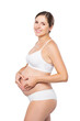 Young pregnant woman in swimsuit. Girl expecting a baby and touching her belly isolated on white background.