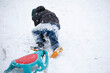 Child in winter. The boy is sledding. A child covered in snow climbs a mountain and pulls a sled behind him.