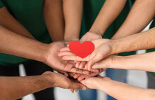 Charity, Support And Volunteering Concept - Close Up Of Volunteers's Hands Holding Red Heart At Distribution Or Refugee Assistance Center