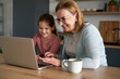 © gpointstudio - Grandmother and her granddaughter using laptop together at home