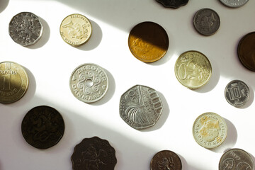 coins of different countries laid out on the surface in rows and illuminated by a strip of light