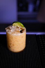 Poster - Vertical shot of a fresh cocktail decorated with lime and coffee beans on a black background