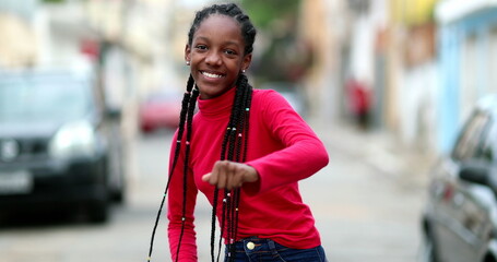 Wall Mural - Happy African teen girl dancing in street. Adolescent teenager female dances