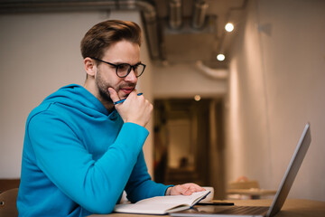 Wall Mural - Skilled male programmer in spectacles developing software on modern netbook technology connect to 4g internet,millennial hipster guy searching content publication in social media using laptop computer