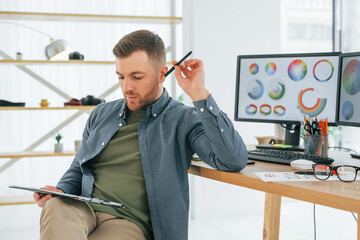 With tablet in hands. Male designer working in the office by using PC