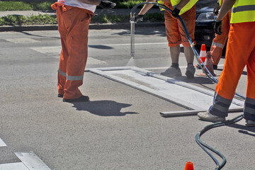 Sticker - Outdoor shot of Workers painting and hand spraying a pedestrian crossing in a  sunny city street