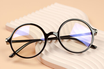 Sticker - Stylish round glasses for vision on a wavy beige podium