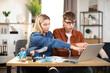 Students, man and woman in casual outfit using laptop during working together. Young business partners cooperating at bright office or working online from home