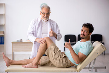 Wall Mural - Young male patient visiting old male doctor