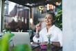 © BullRun - Half length portrait of cheerful Caucasian female digital nomad having break at table on cafe terrace, joyful woman freelancer sitting with laptop computer for doing distance job and smiling at camera