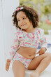 © EZ PHOTOS - Portrait of smiling baby girl with afro hair style and sunglasses in a colourful swimsuit outfit posing by the pool. Afro-American and Afro-Brazilian children summer concept with copy space.